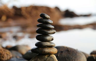 A stack of smooth stones artfully balanced by a waterside, evoking tranquility and zen.
